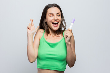 Young woman hoping the pregnancy test will be positive. On white background.