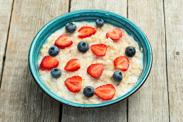 Homemade breakfast . Oatmeal with milk and berries . Top view