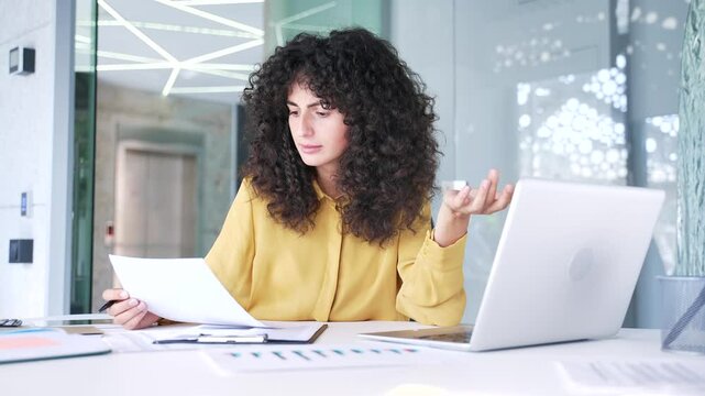 Frustrated female financier unhappy with financial results checking documents on computer sitting at desk at workplace in business office. Upset puzzled businesswoman dissatisfied with bad indicators