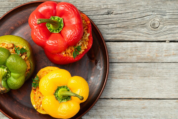 Baked stuffed pepper ( paprika ) with rice , carrot and meat . Top view on rustic background