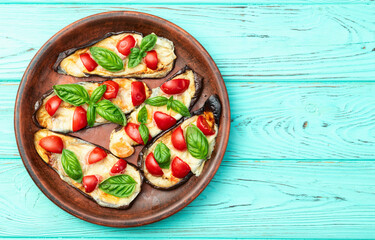 Italian mini pizza . Aubergine (eggplant ) with mozzarella cheese and basil . On rustic background