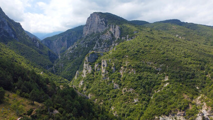 Zeus Bath, Olympos Mountain Gorge with Rugged Cliffs and Lush Forests. Highlights a rugged mountain gorge surrounded by lush forests and dramatic cliffs. 