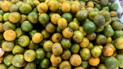 a stack of green orange fruit at fruit shop