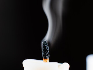 A candle wick emits smoke after being put out