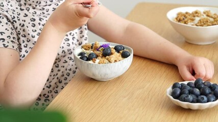 Little girl eats healthy breakfast with granola, yogurt, berries and milk - Powered by Adobe