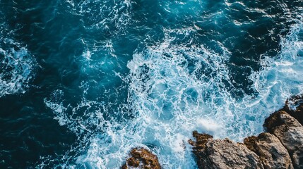 Obraz premium Mesmerizing Aerial View of Deep Blue Ocean Waves Crashing Against Rugged Coastal Rocks: A Captivating Seascape