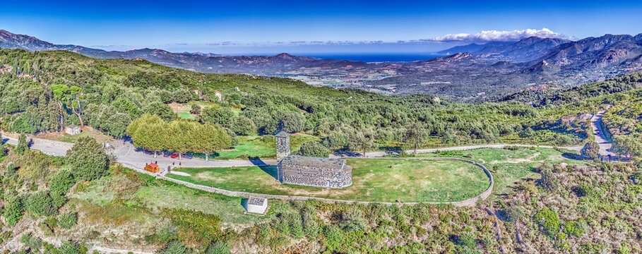 Aerial view of the historic San Michele de Murato church in Corsica with scenic landscape towards Cap Corse