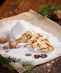 Slices of Christmas stollen on wooden background. Traditional Christmas festive pastry dessert. Stollen is treat for Christmas. Still life. German fruit bread.