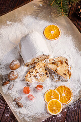 Slices of Christmas stollen on wooden background. Traditional Christmas festive pastry dessert. Stollen is treat for Christmas