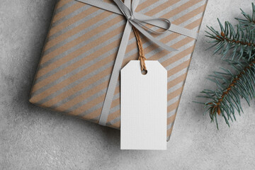 Christmas flat lay, blank paper gift tag with gift box, top view with copy space for tag design