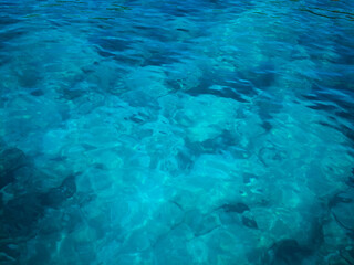 Serene view of crystal-clear blue ocean water under sunlight.