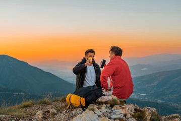 Naklejka premium Two friends travelers taking a break at the top of the mountain during the hike adventure travel.