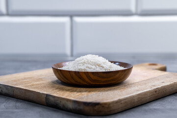 Wooden bowl of rice on rustic cutting board
