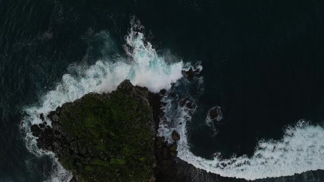 4k video footage - Aerial view of Watu Karung Beach, Pacitan, East Java, Indonesia with crashing waves during cloudy day. Cape with cliffs by the sea and green plants around at tropical island