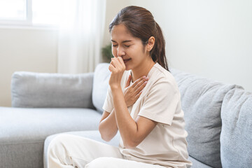 Health care of coronavirus concept, unhealthy and sickness, asian young woman, girl unwell and coughing, hand touch her neck, female sore throat suffering with symptom cough feeling bad at home.