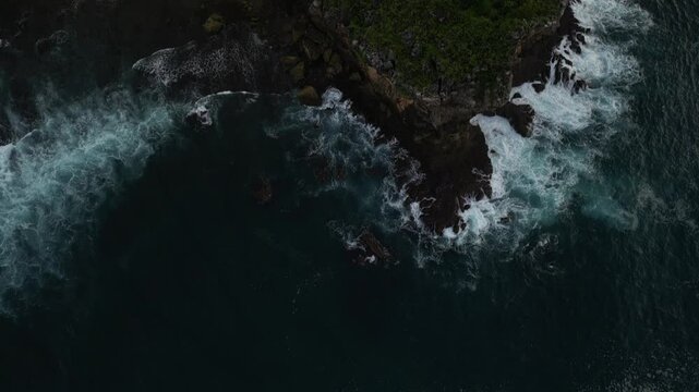 4k video footage - Aerial view of Watu Karung Beach, Pacitan, East Java, Indonesia with crashing waves during cloudy day. Cape with cliffs by the sea and green plants around at tropical island