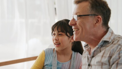 Grandfather and granddaughter together watch interesting entertainment media on TV. Old senior use technology communicate with young generation cross generation gap strengthen family bond. Divergence.