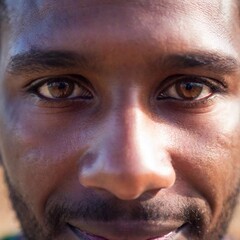 Fototapeta premium Extreme closeup portrait of an Ethnic-themed of a black man in a traditional village, with a focus pull and POV perspective. Photo-realistic.