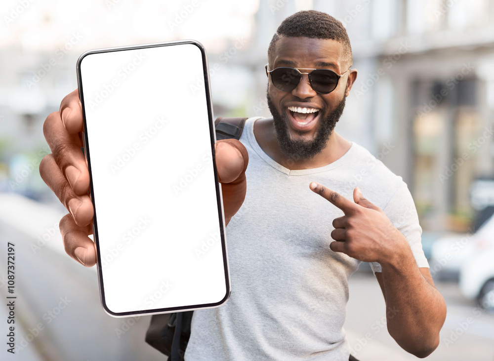 Poster great offer. portrait of excited black man standing outdoors holding big phone with white blank scre