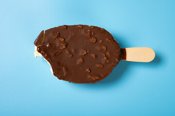 a chocolate outer popsicle with a bite on blue background
