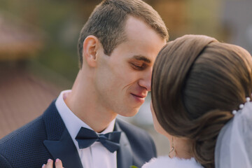 A man and woman are kissing each other's noses. The man is wearing a suit and tie