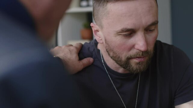 Close-up shot of stressed veteran soldier getting support from his male therapist during counselling session at his office