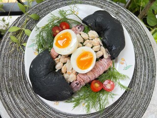 Crab, mantis shrimp and soft boiled with egg black charcoal bagel