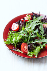 Salad with fresh tomatoes and arugula on a bright wooden background. Close up. Copy space.