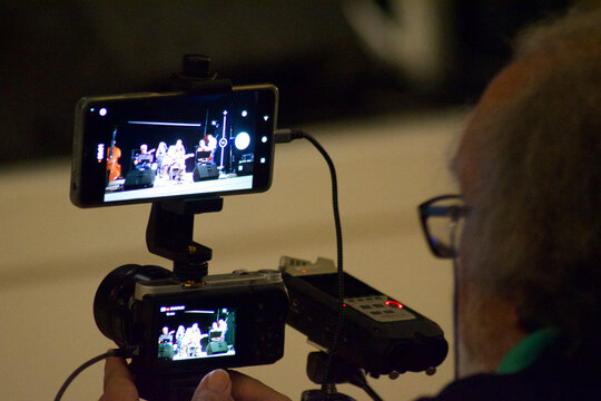 audience and journalist shooting musicians in a theatre concert with mobile phone