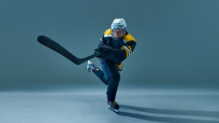Focused man, ice hockey player captured in motion, powerfully skating across rink, holding stick....
