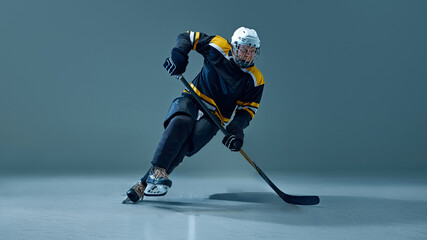 Man, hockey player skating forward with determination, gripping stick, during gameplay, dressed in...