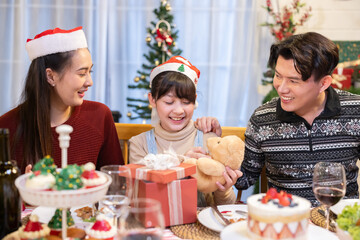 Asian daughter open her Christmas gift box with her parent