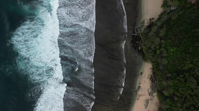 4k video footage - Aerial view of Watu Karung Beach, Pacitan, East Java, Indonesia with crashing waves during cloudy day. Cape with cliffs by the sea and green plants around at tropical island