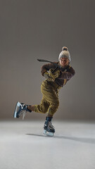Full-length vertical image of man in retro clothes, cozy warm sweater, pants and hat, playing hockey. Concept of sport, game, tournament, action, competition