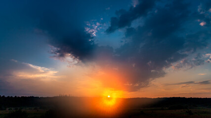 Real majestic sunrise sundown sky background with gentle colorful clouds without birds over forest.