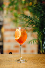 Aperol Spritz Cocktail with Orange Slice Garnish Vertical Image On The Bar Counter Against The Brick Wall