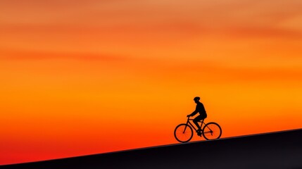 Obraz premium A silhouette of a cyclist riding against a vibrant sunset backdrop, capturing the essence of adventure and tranquility.