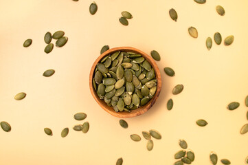 Fresh pumpkin seeds in a wooden bowl on beige background, top view flat lay. Organic eco healthy seeds, superfood, diet food, healthy vegetarian food. Green Smoothie Ingredient