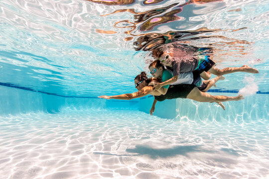 Woman with her kids swimming underwater in a pool