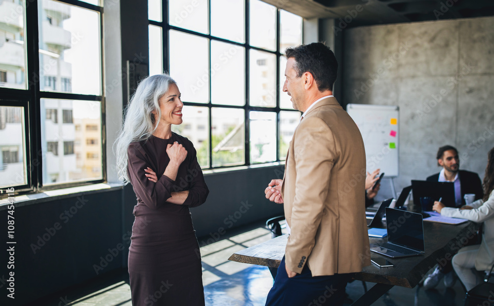 Poster a man and a woman engage in a lively conversation in a bright, open office space. their expressions 