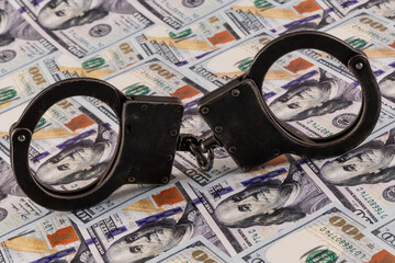 Handcuffs against the background of 100 US dollar bills