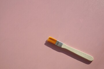 Large paint brush against pink backdrop