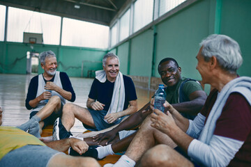 Naklejka premium Senior men taking a break from playing basketball in an indoor gym