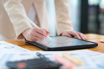 Close-up of hand signing electronic documents on a tablet with a digital pen for online workflows