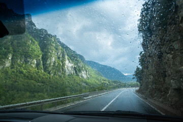 A wet road on a cloudy and rainy day seen from inside a vehicle. Concept of driving, transportation and caution on the road © LaMorenita