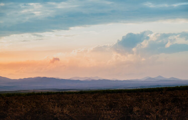 Mountain Landscape background of a cloudy sky in which the evening light produces beautiful and soft colors. The general appearance is that of a natural watercolor in a concept of relaxation