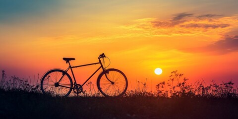 Obraz premium Silhouette of a bicycle against a stunning sunrise backdrop. The bicycle is positioned on a hill, capturing the beauty of the sunrise in soft focus, showcasing the allure of cycling during dawn.