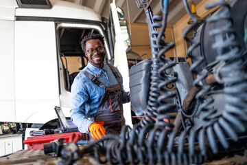 Experienced mechanic repairing trucks inside garage workshop. Trucks service and maintenance.