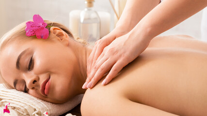 Woman enjoying massage with oil, flowers and aroma sticks