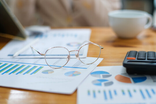 Close-up of financial charts, eyeglasses, and calculator on a desk for data analysis and planning